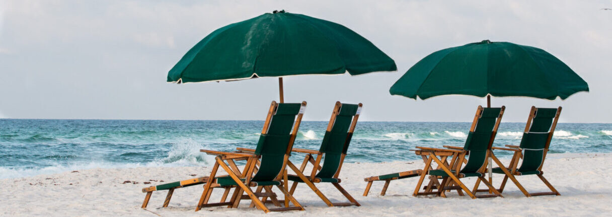 Beach chairs and umbrellas on beach with waves and sand.