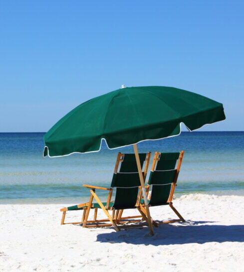 two chairs and umbrella on white sand beach